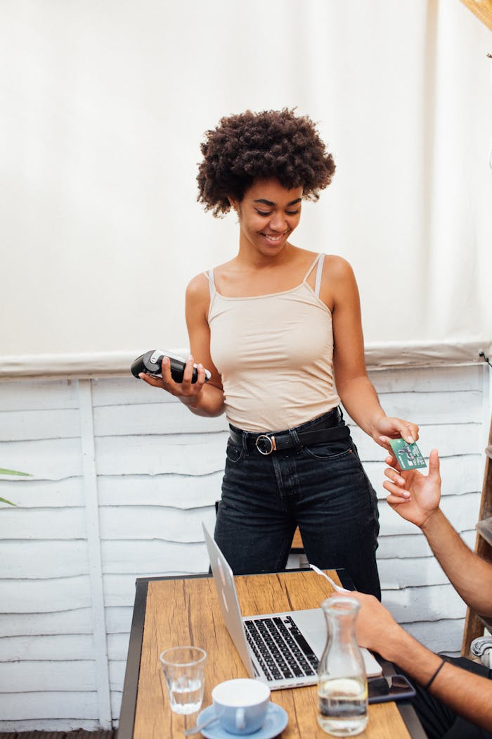 about-01 Woman smiling while handling payment transaction in a café setting.